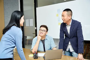 Two men and one woman talking to each other in conference room.